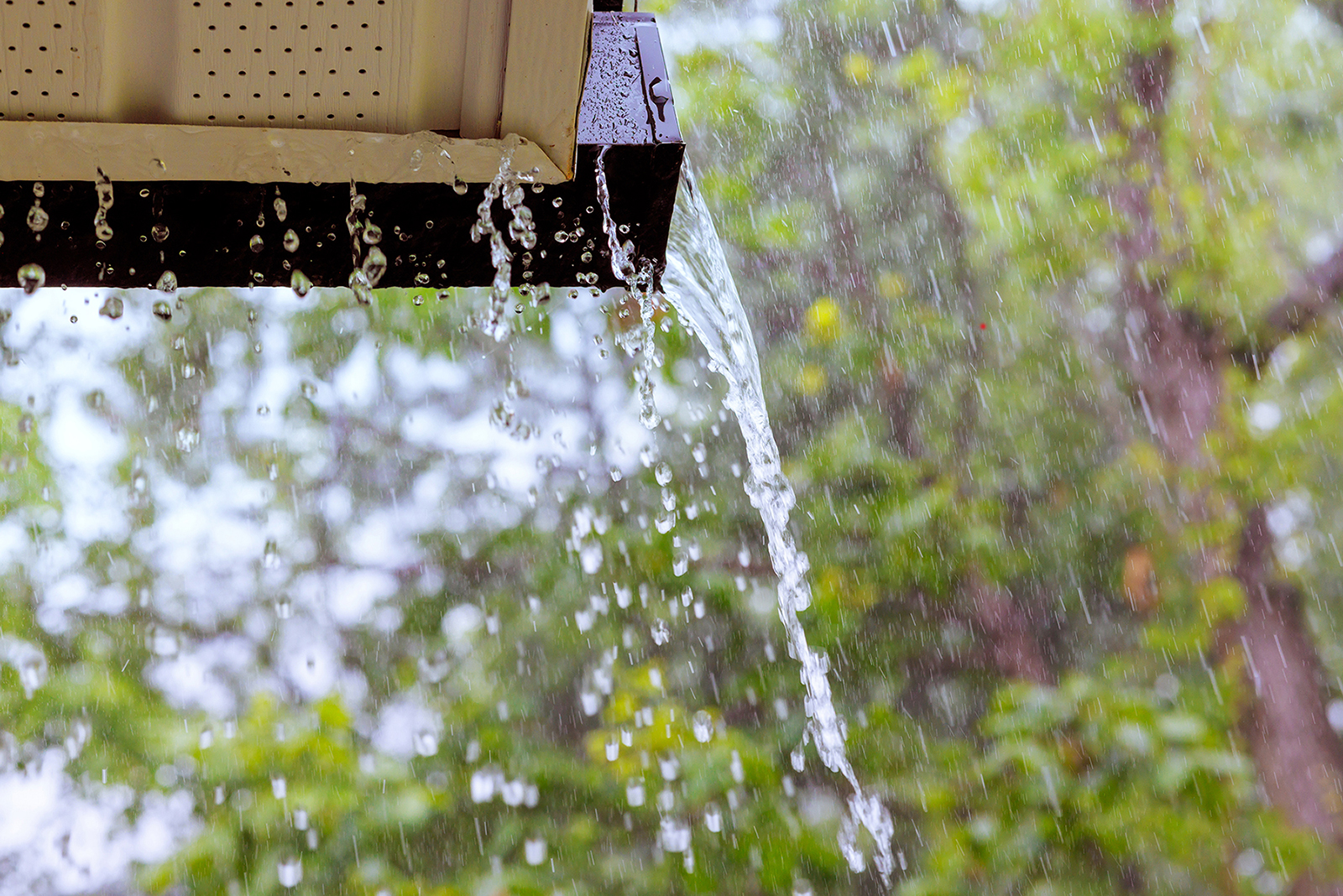 During heavy rain, water cascades from the overflowing gutters.